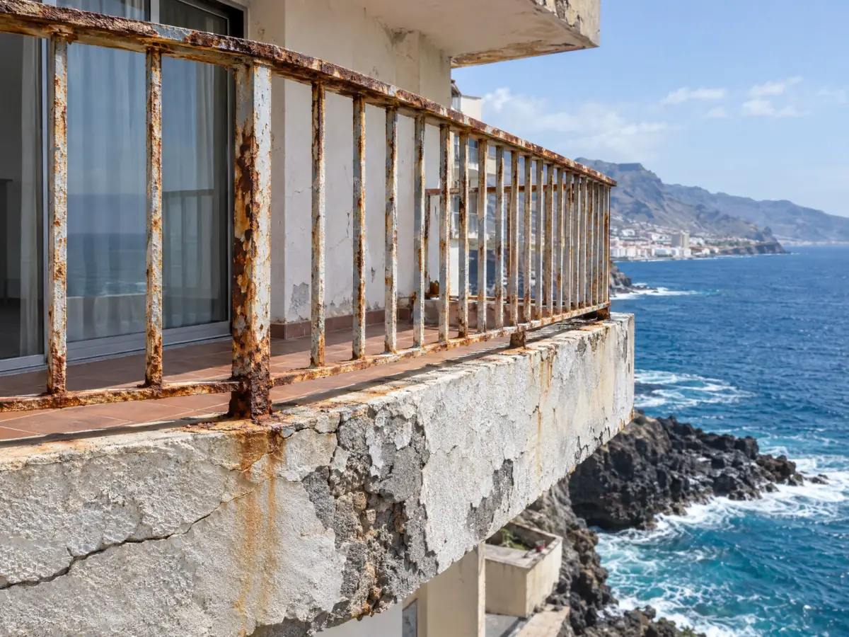 Barandilla corroída y revestimiento dañado por el salitre en un edificio del frente marítimo