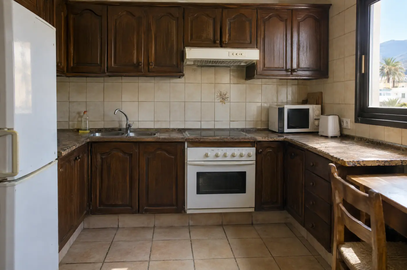Cocina de un piso en Tenerife antes de la reforma: muebles de madera oscura, azulejo beige y electrodomésticos antiguos
